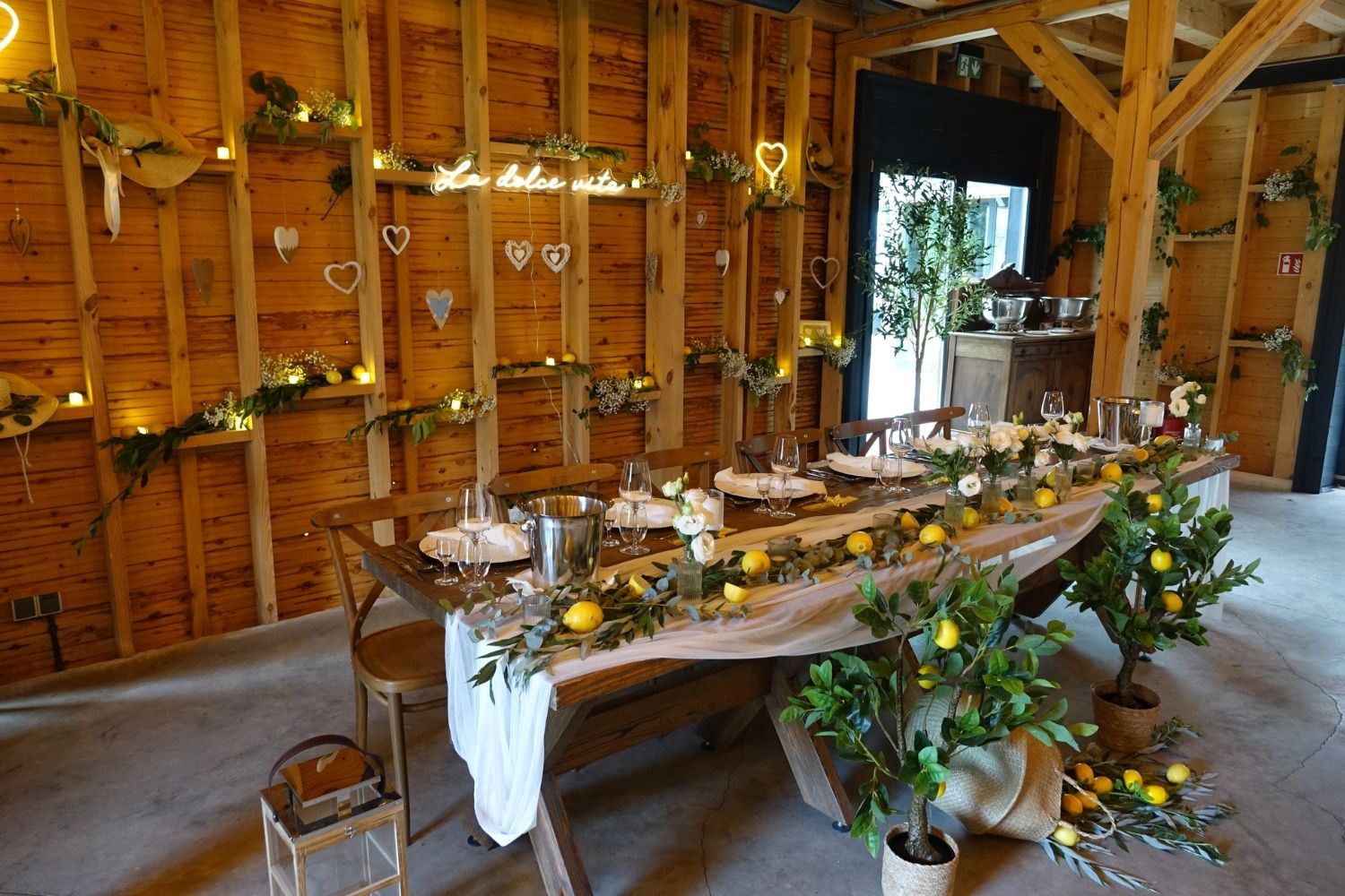 Rustykalna sala weselna z długim stołem udekorowanym w stylu włoskim z cytrynami i zielenią.